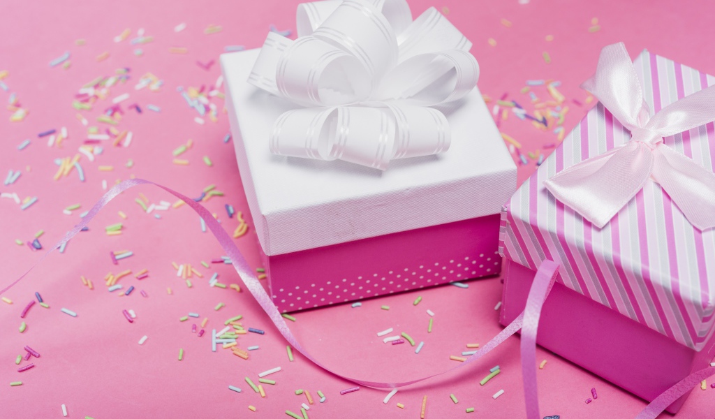 Две подарочные коробки с бантами на розовом фоне