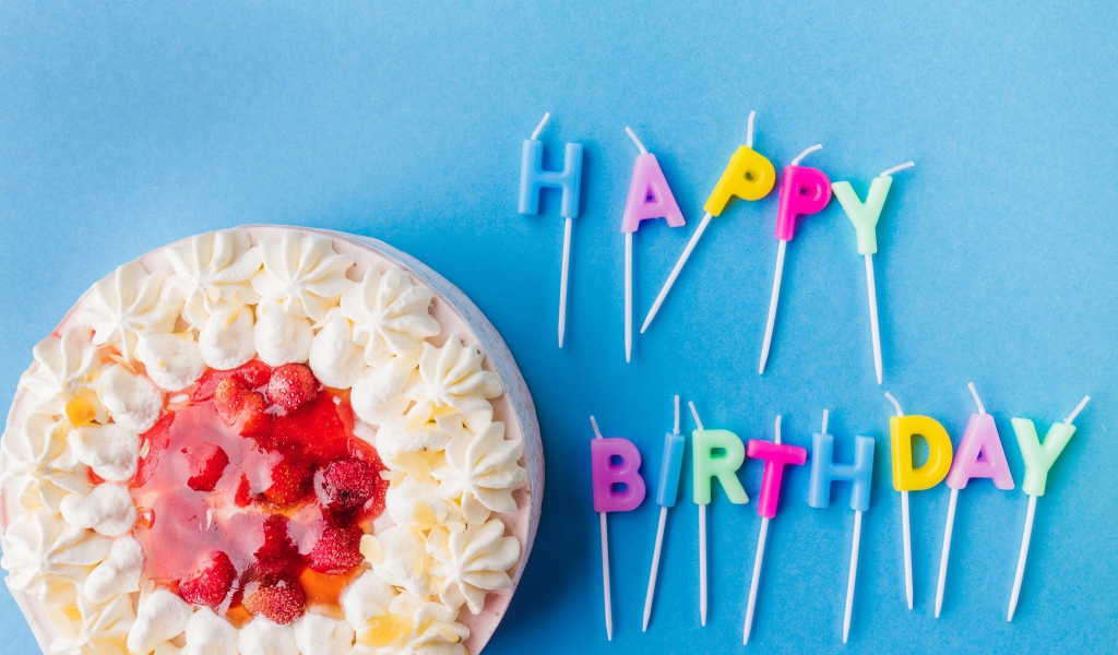 Beautiful cake with cream and strawberries on a blue background with candles for birthday