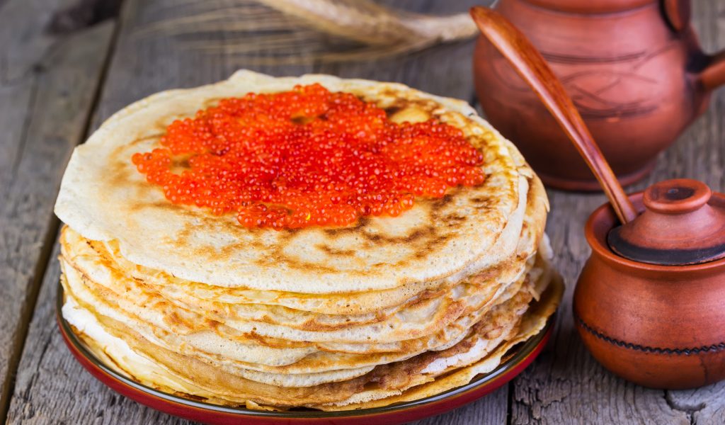 Стопка блинов с красной икрой на деревянном столе угощение на Масленицу