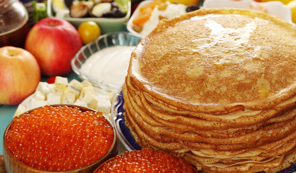 Румяные тонкие блины на столе с красной икрой на Масленицу