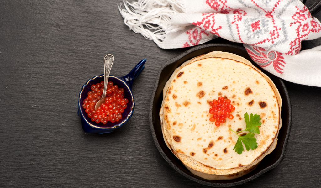 Тонкие блины с красной икрой на столе вид сверху