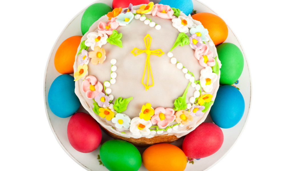 Красивый пасхальный кулич с цветами и разноцветными крашеными яйцами на белом фоне