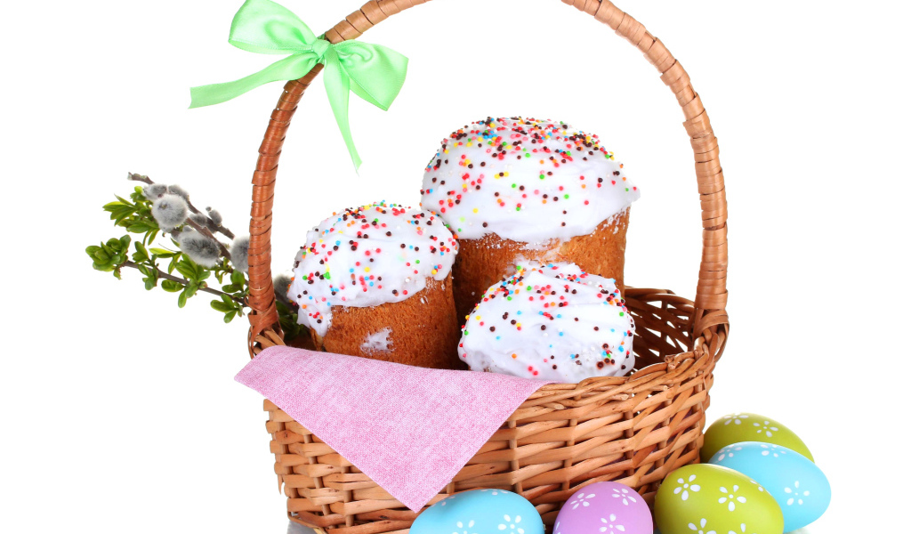 Пасхальные куличи в корзине с крашеными яйцами на белом фоне