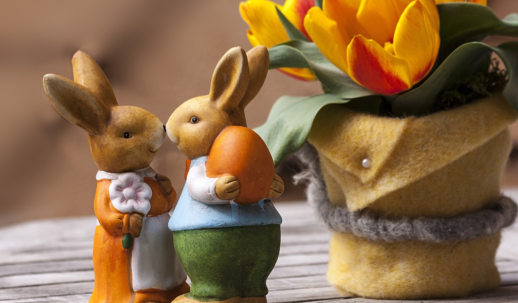 Статуэтки пасхальных кроликов на столе с тюльпанами