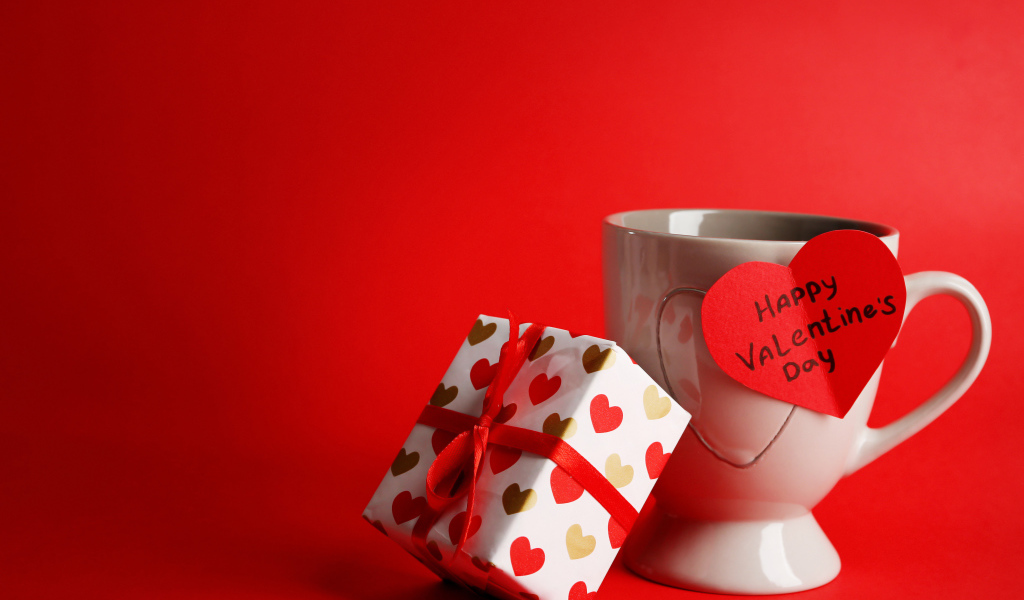 Чашка с подарком и валентинкой на красном фоне на 14 февраля