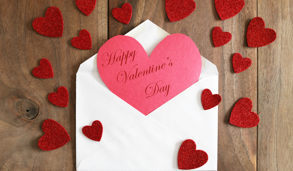 Белый конверт с валентинкой на деревянном столе с красными сердечками на 14 февраля