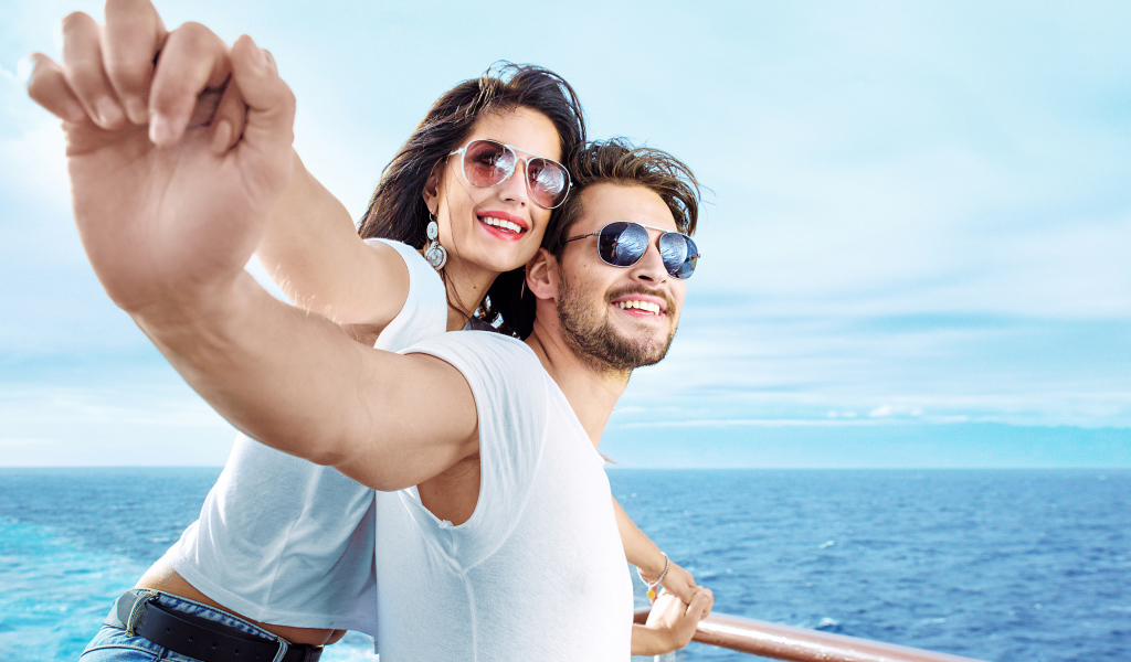 Влюбленная пара держится за руки на фоне моря