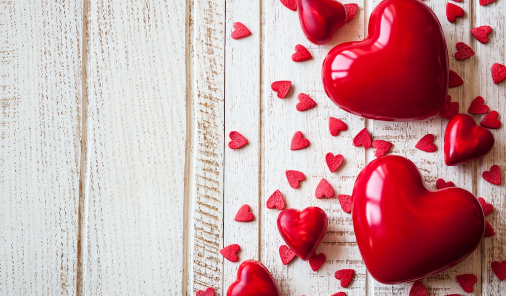 Большие и маленькие  красные  сердечки на деревянном фоне