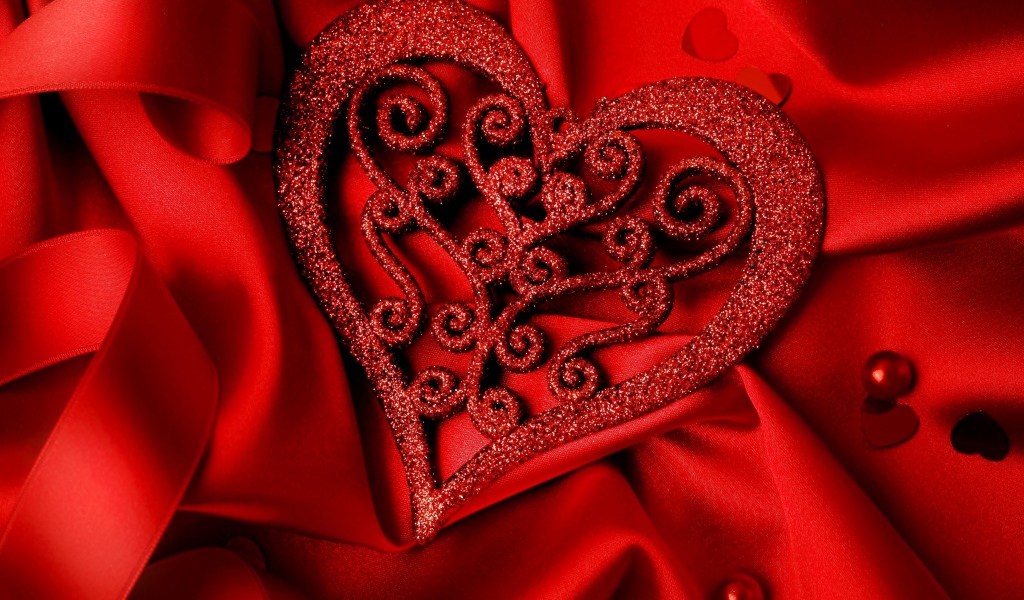 Блестящее сердце на красной атласной ткани 