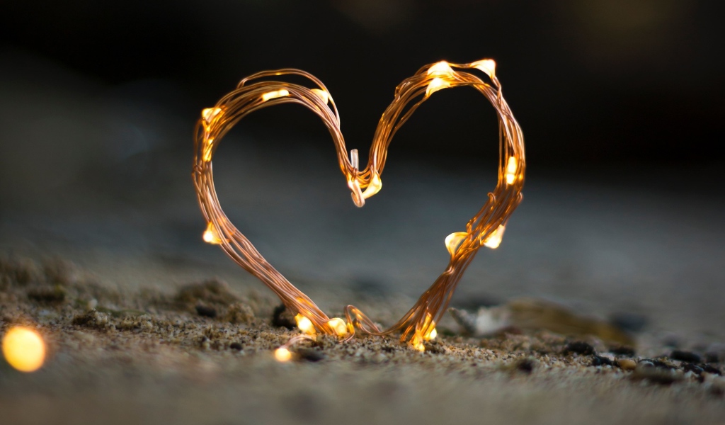 Сердце из гирлянды на песке