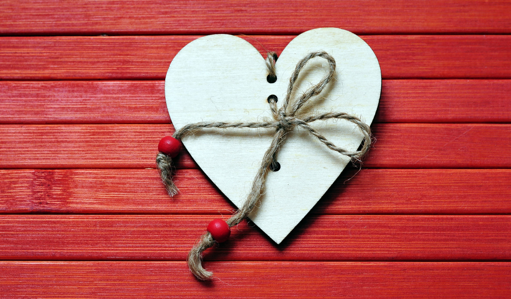 Сердце с веревкой на красном деревянном фоне