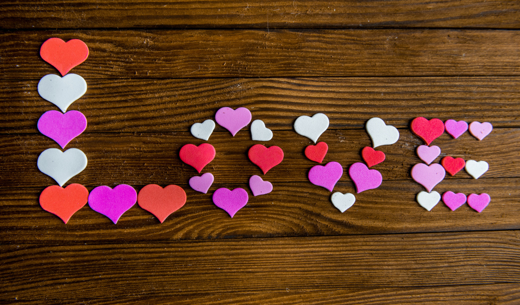 Надпись любовь из разноцветных сердец на деревянном столе