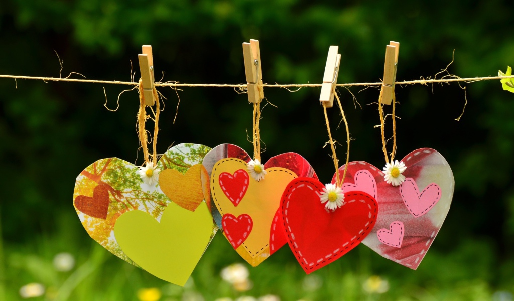 Бумажные сердечки висят на веревке на прищепках