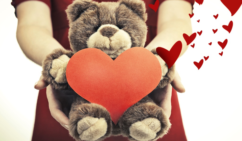 Плюшевый медведь с большим красным сердцем в руках