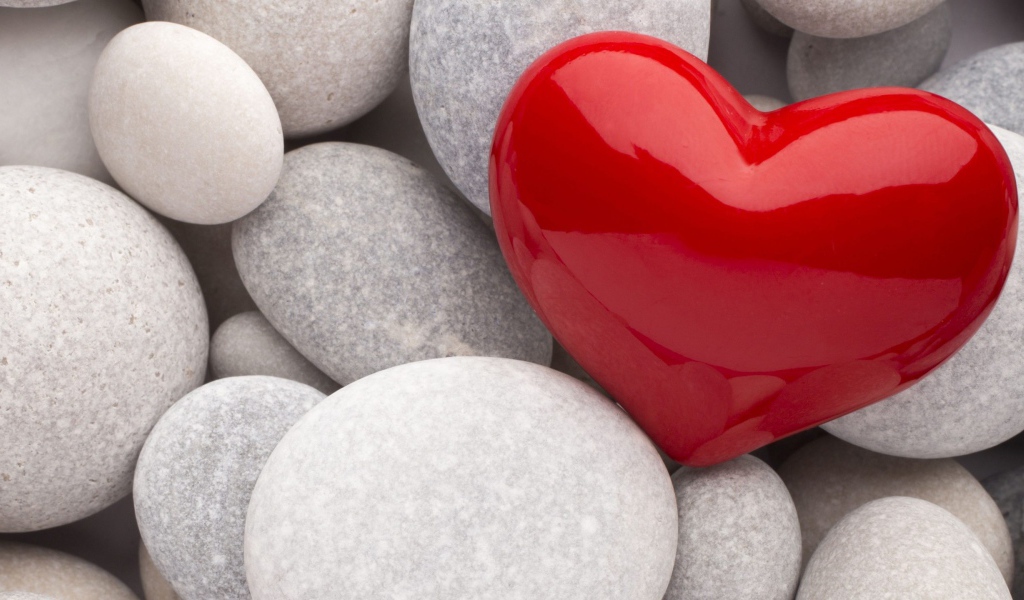 Красное сердце лежит на серых камнях 