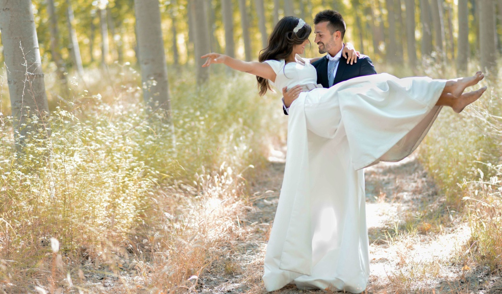 Парень жених держит на руках невесту в белом платье