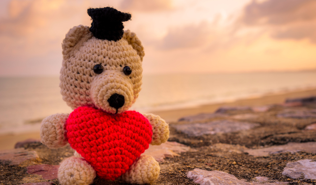 Игрушечный медведь с красным сердцем на фоне неба