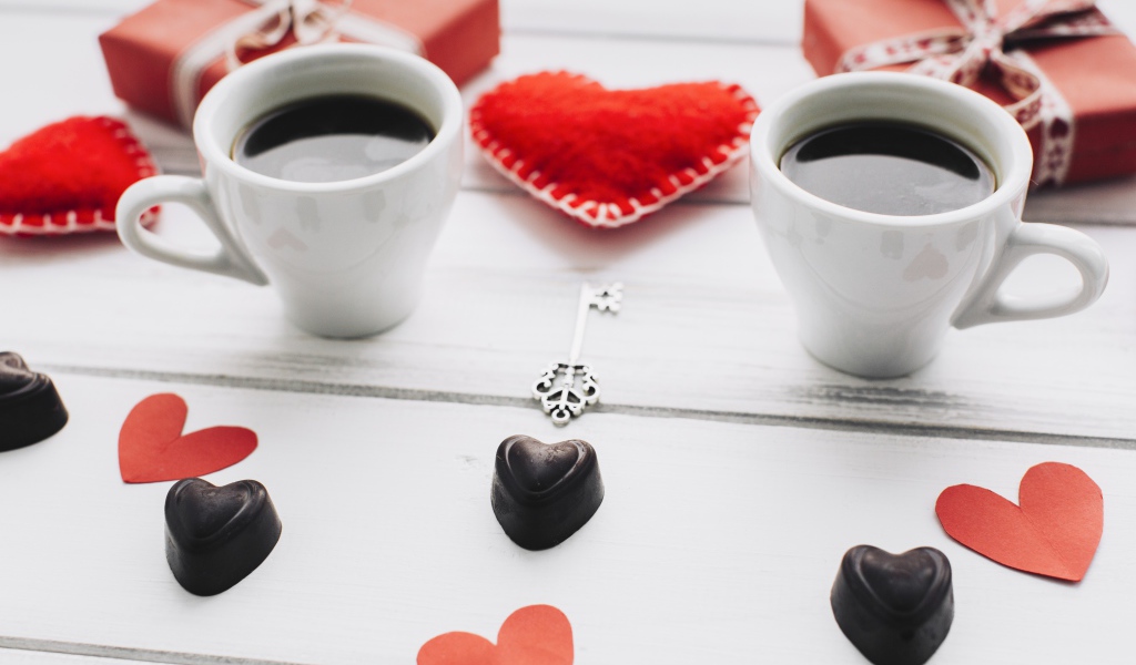 Две чашки кофе на столе с подарками, конфетами и сердечками