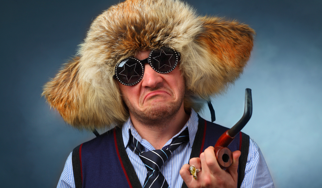 Мужчина в меховой шапке в модных очках с трубкой в руке