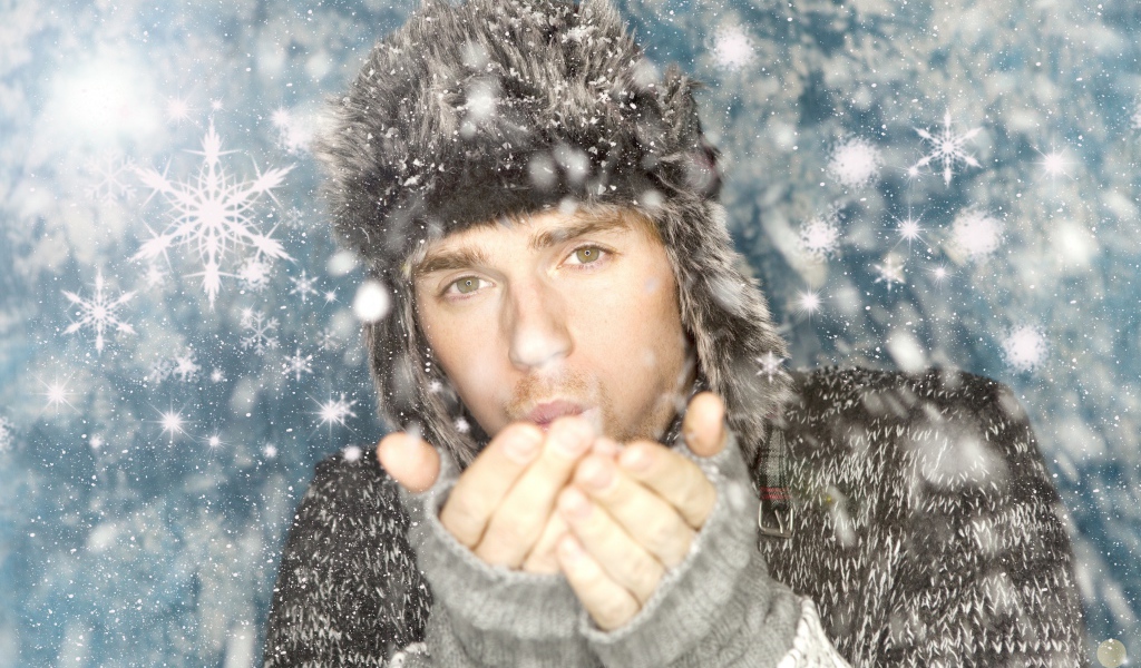 Молодой парень в теплой шапке мерзнет зимой