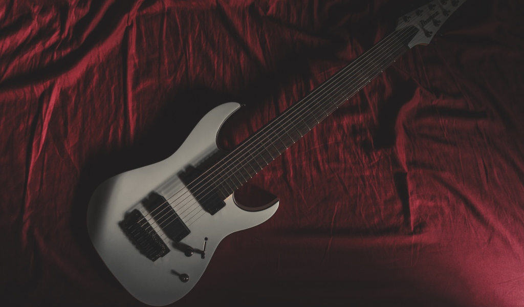 Гитара лежит на красном покрывале