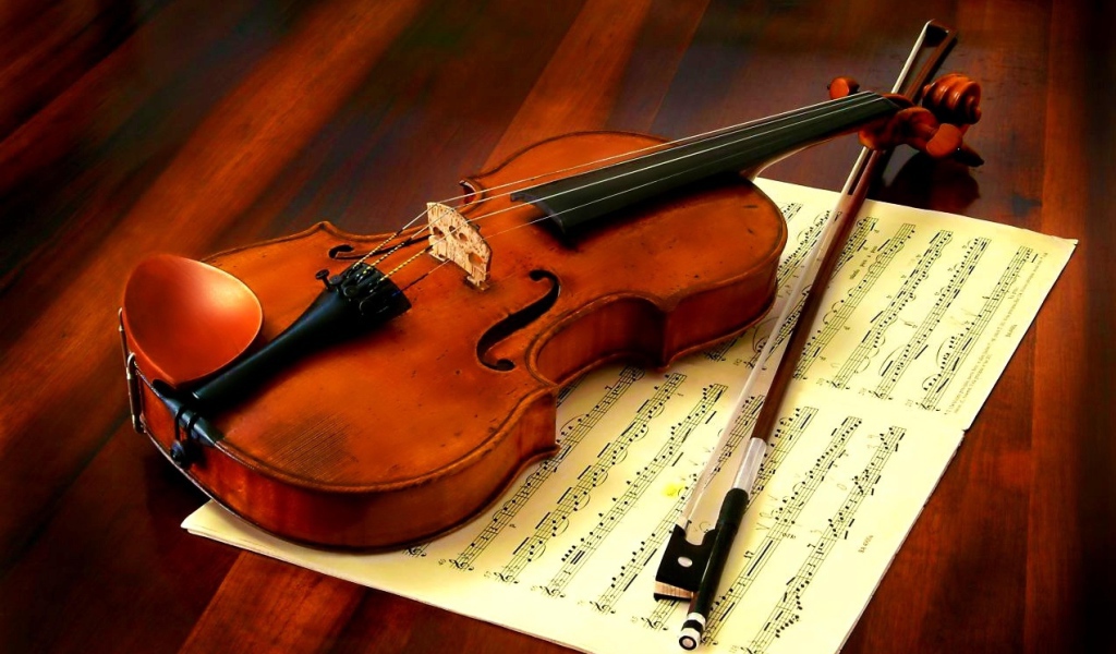 Скрипка со смычком лежат на нотной тетради