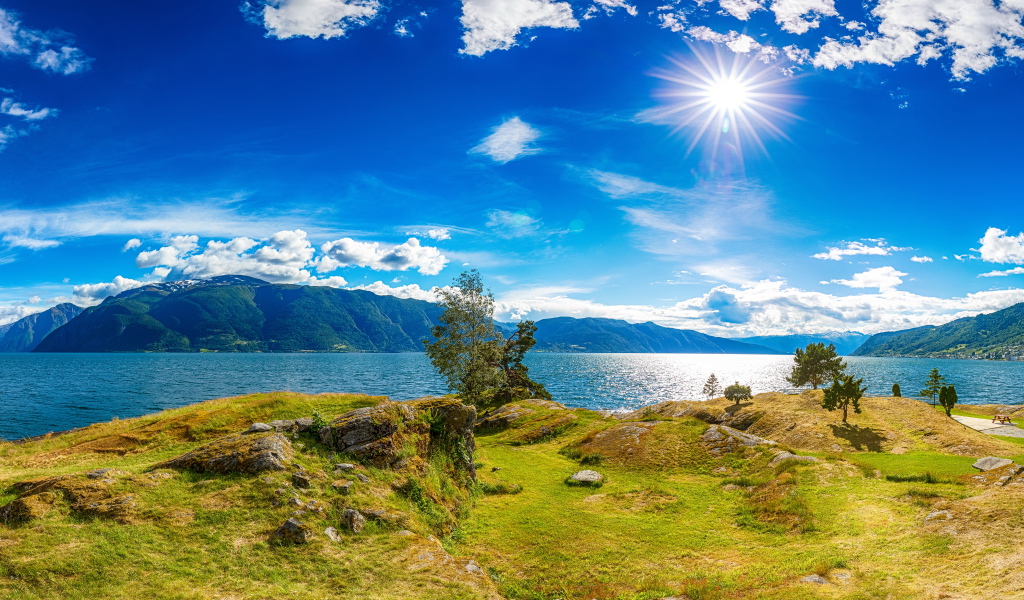 Красивое яркое солнце в голубом небе над горами и водой, Исландия