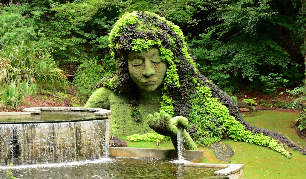 Красивый водопад в парке со скульптурой 