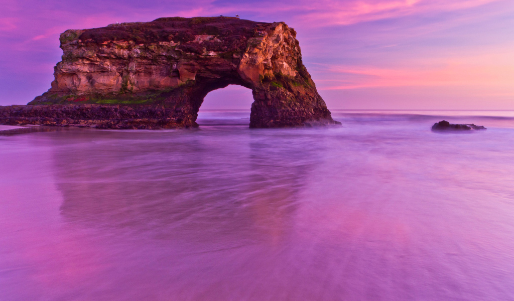 Гора с аркой в океане на фоне красивого неба