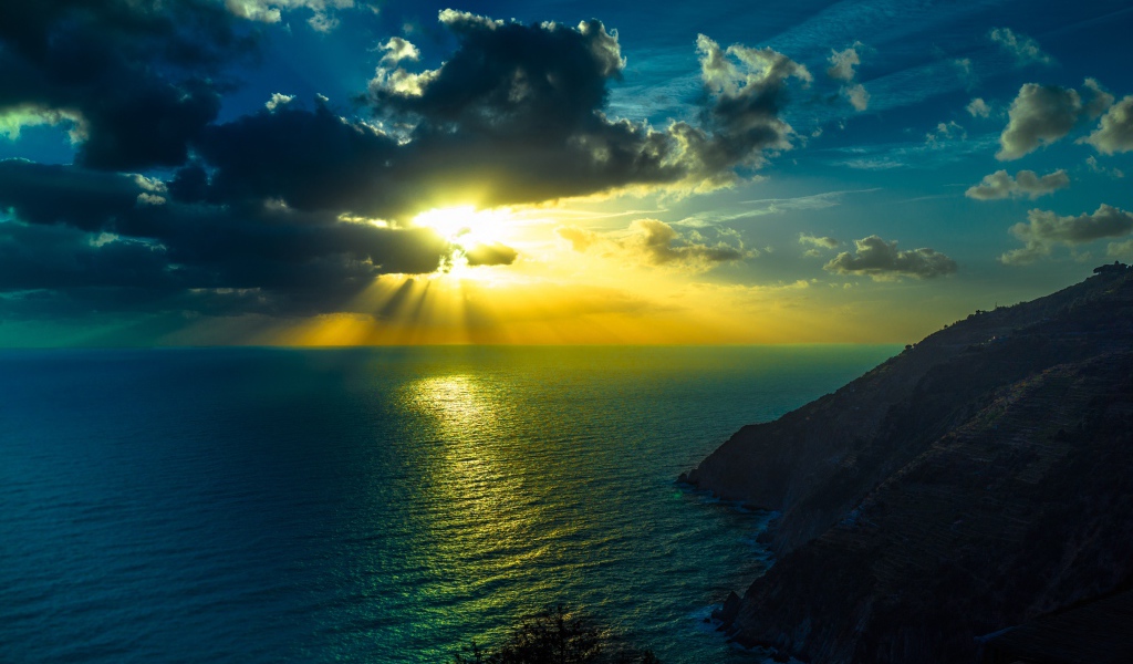 Лучи яркого солнца пробиваются сквозь облака над морем