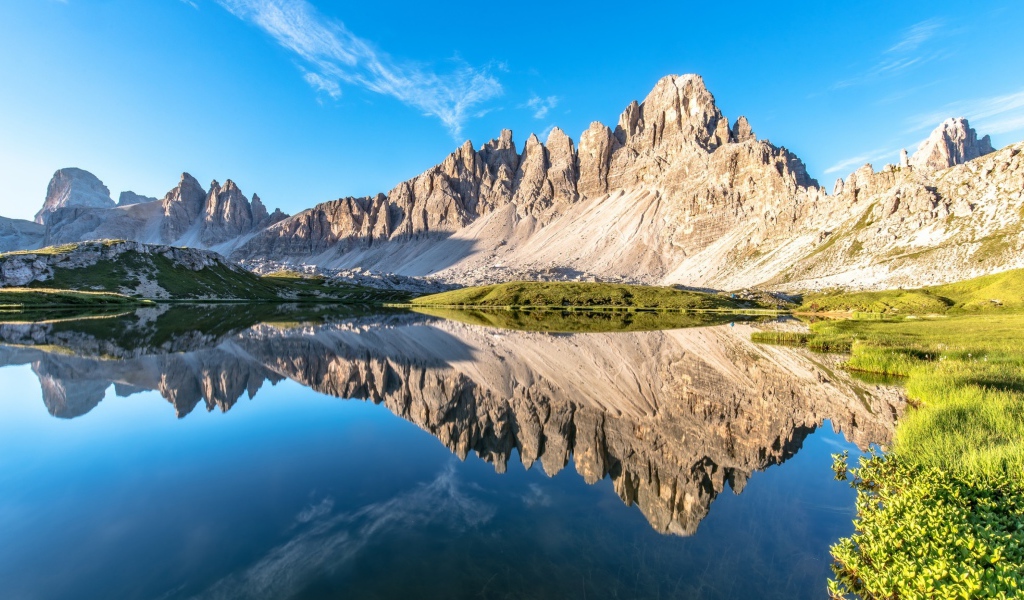 Горы и голубое небо отражаются в чистой воде 