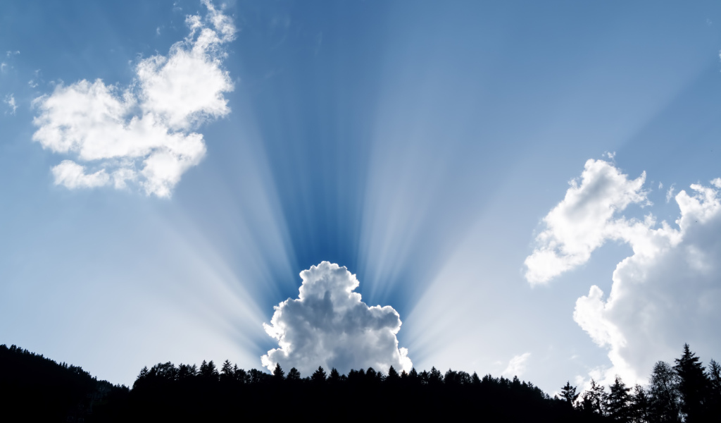 Лучи солнца пробиваются сквозь белые облака в голубом небе 