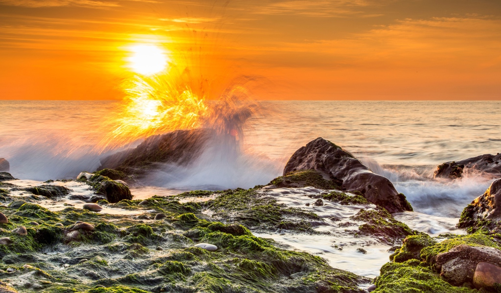 Бушующие волны в море бьются об камни на закате