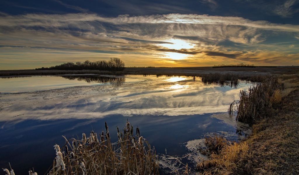 Белые облака отражаются в воде на закате солнца