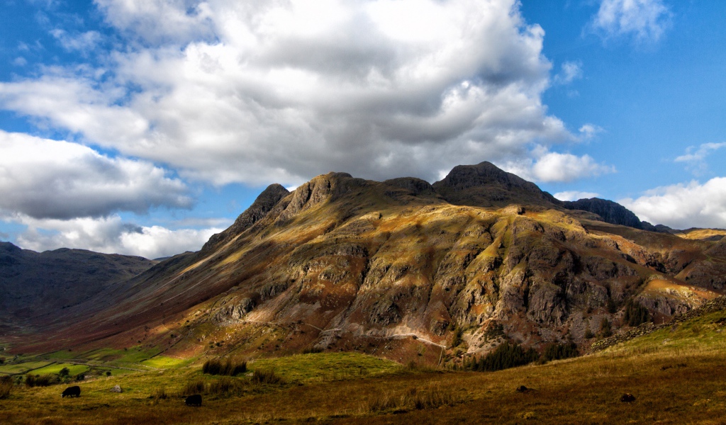 Белые пушистые облака над горой 