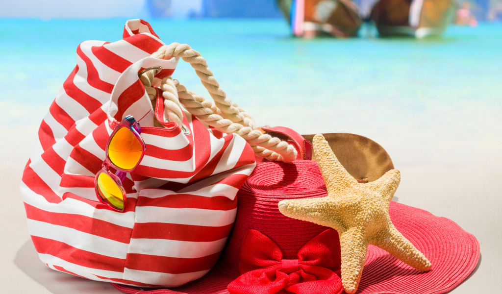 Большая красная шляпа с сумкой и морской звездой на пляже