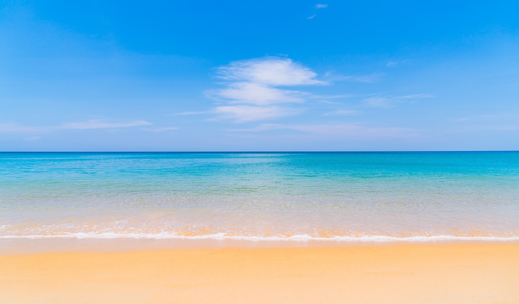 Желтый песок у лазурного океана под голубым небом