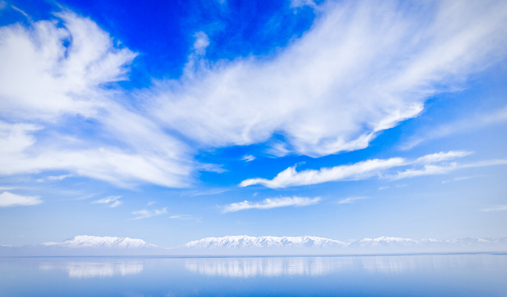 Красивые белые облака над водой около заснеженных гор