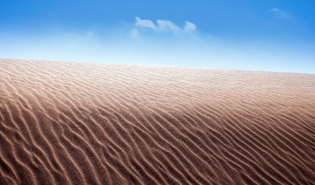 Песок в пустыне на фоне голубого неба