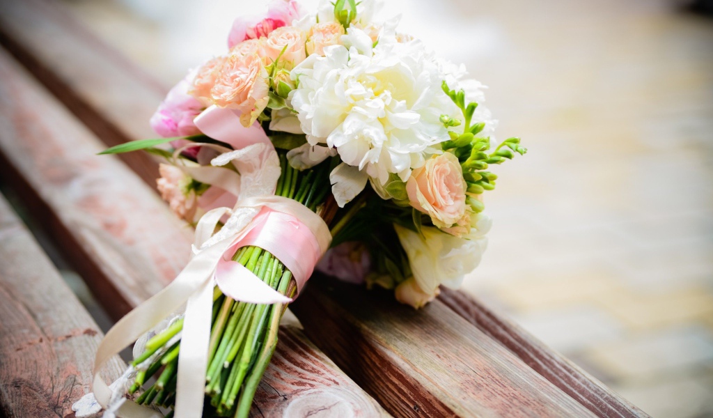 Красивый свадебный букет лежит на деревянной лавке