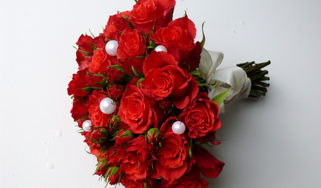 Красивый букет красных роз с жемчужными бусинами на сером фоне