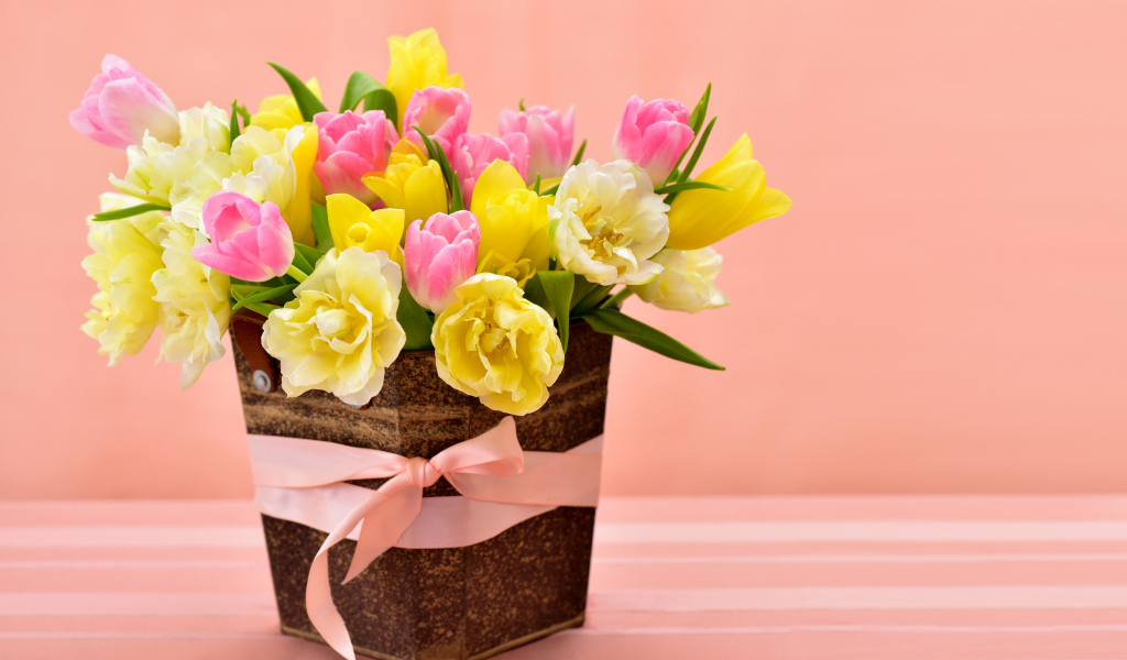 Букет красивых разноцветных тюльпанов в вазе на розовом фоне