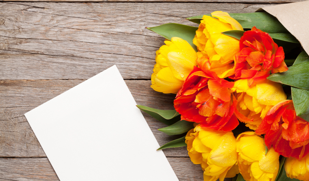 Букет желтых тюльпанов на столе с листом бумаги