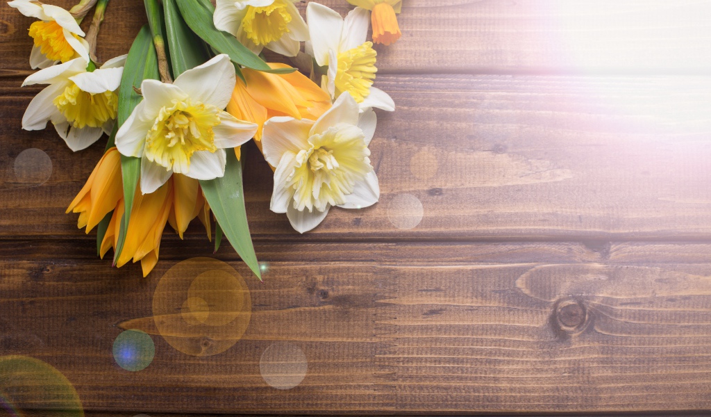 Нарциссы и желтые тюльпаны на деревянном фоне