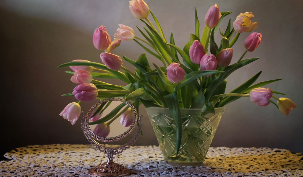 Розовые тюльпаны в стеклянной вазе на столе с зеркалом 