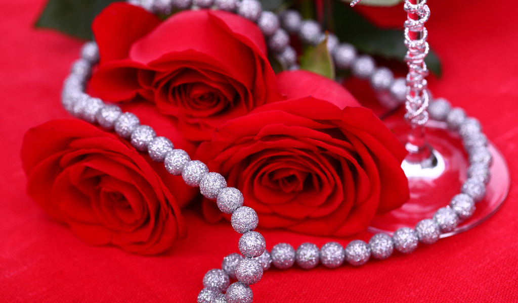 Три красные розы с украшением на красном фоне