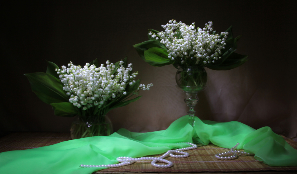 Два букета ландышей с бусами на столе 