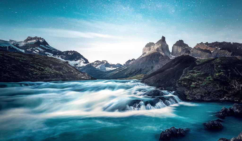 Быстрая вода к реке у гор на фоне голубого неба 