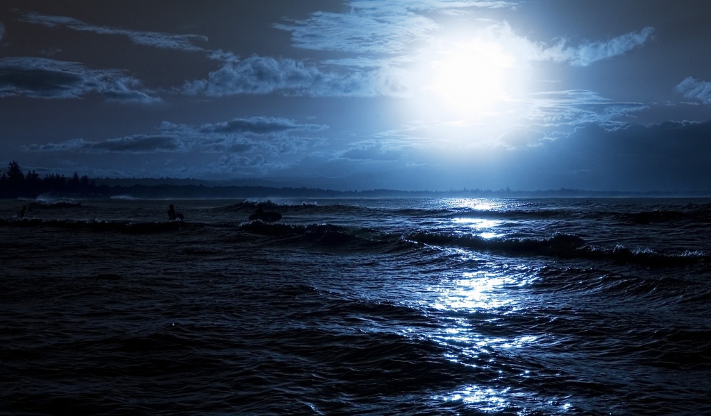 Яркая луна освещает волны на берегу моря