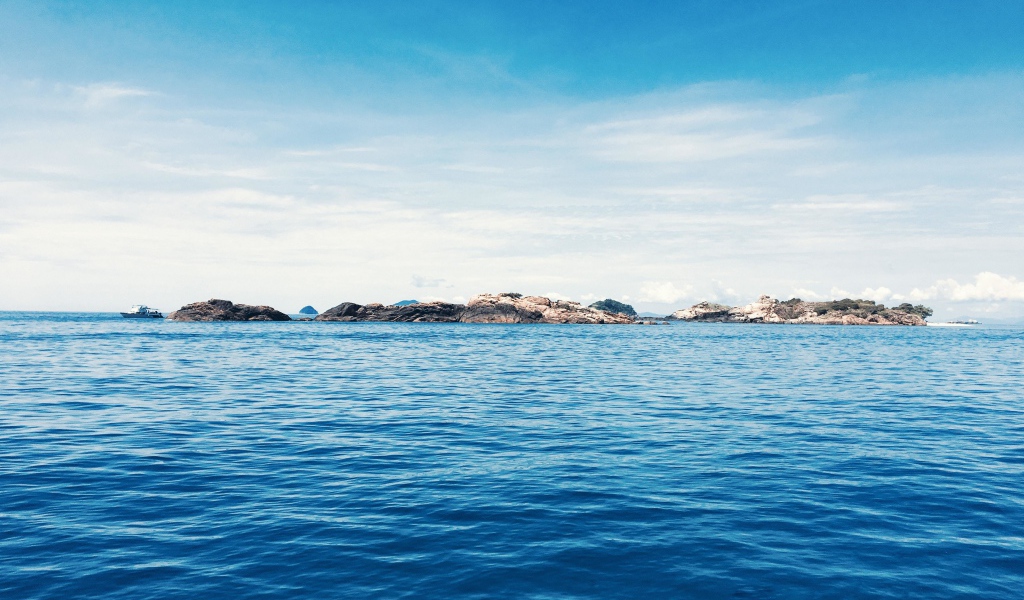 Спокойное синее море со скалами на горизонте